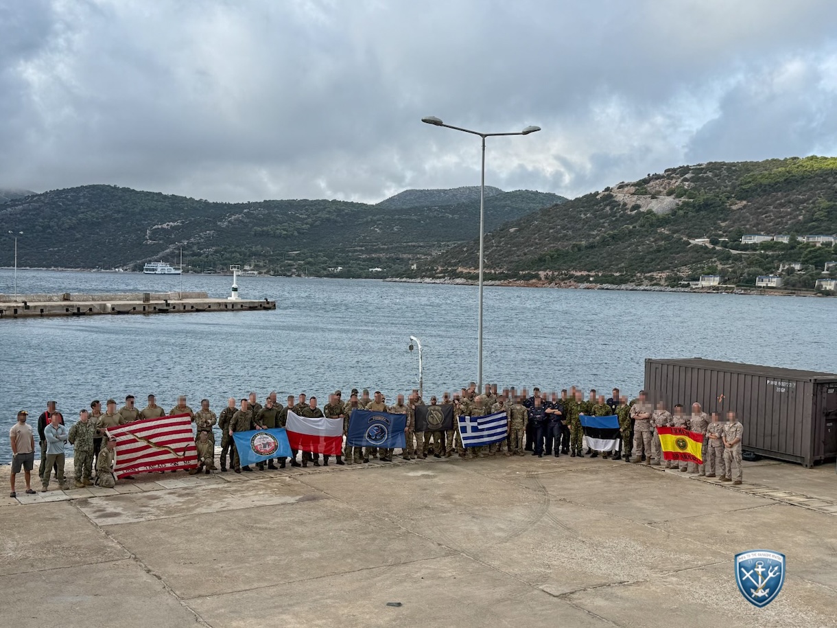 Ομάδα στρατιωτικών με στολές παραλλαγής και εθνικές σημαίες σε παραθαλάσσια προβλήτα